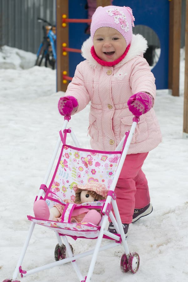 La Niña Juega Con Un Carro De Bebé Del Juguete En El Invierno En Foto de archivo - Imagen de sonrisa, carro: 90083730