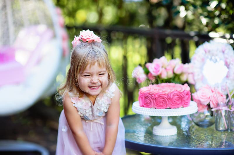 La niña celebra el partido del feliz cumpleaños con la rosa al aire libre
