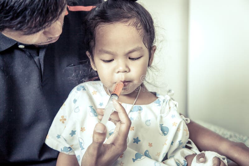 La niña del niño consigue la medicina con una jeringuilla en su boca fotografía de archivo libre de regalías La niña del niño consigue la medicina con una jeringuilla en su boca fotografía de archivo libre de regalías