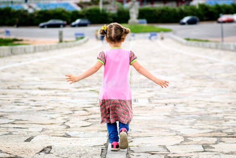 La niña está corriendo en la 'promenade' pavimentada piedra imagen de archivo libre de regalías La niña está corriendo en la 'promenade' pavimentada piedra imagen de archivo libre de regalías