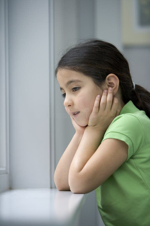 La niña está mirando fuera de la ventana fotografía de archivo libre de regalías La niña está mirando fuera de la ventana fotografía de archivo libre de regalías