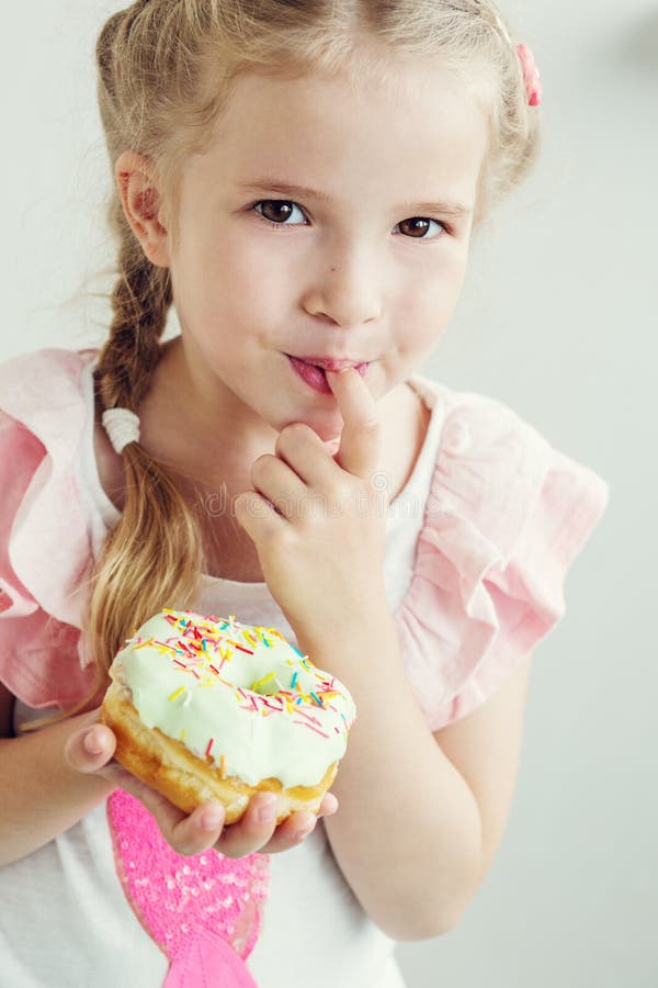 Happy little girl eats the sweet donut on a white background. Happy little girl eats the sweet donut on a white background