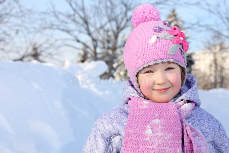 La niña feliz en bufanda y sombrero rosados mira la cámara foto de archivo La niña feliz en bufanda y sombrero rosados mira la cámara foto de archivo