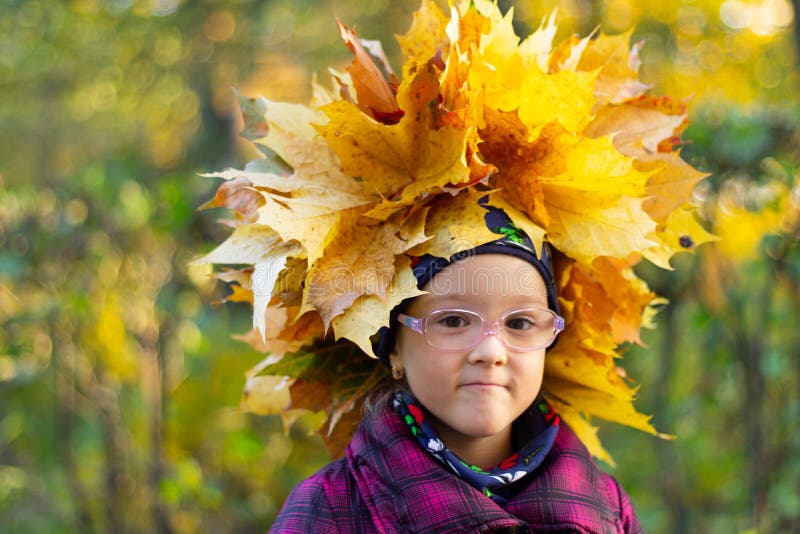La niña feliz juega con las hojas de otoño en el parque foto de archivo La niña feliz juega con las hojas de otoño en el parque foto de archivo