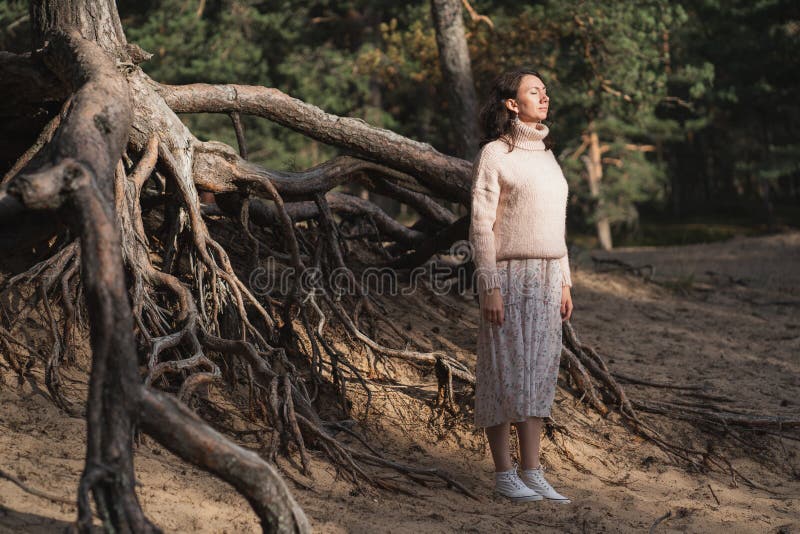 La niña medita en el bosque. la niña recibe vitamina d del sol. raíces enormes del árbol. alivio de estrés en foto de archivo