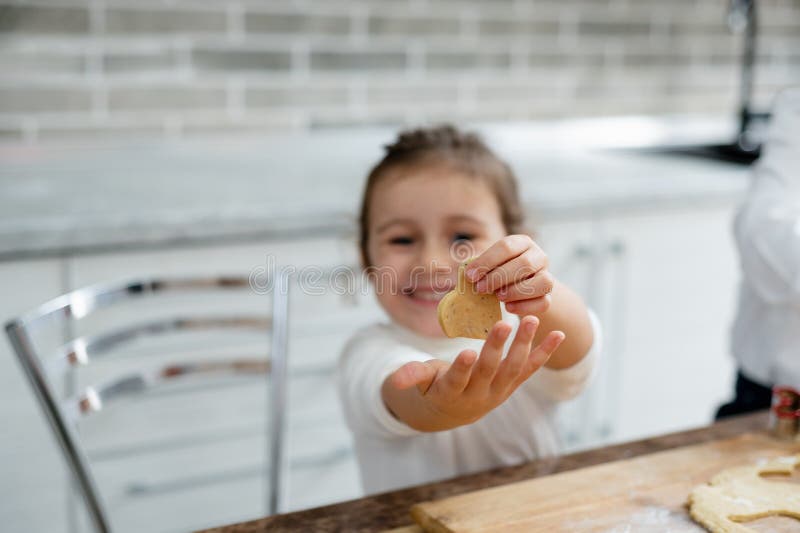 La niña muestra a la cámara un poco corazón de masa y de las sonrisas foto de archivo libre de regalías