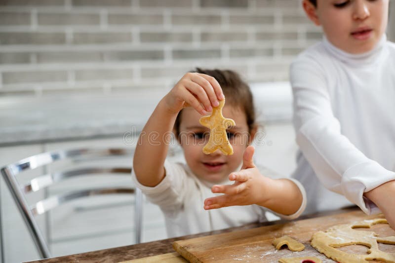 La niña muestra la elaboración de galletas en forma de hombre imagen de archivo libre de regalías