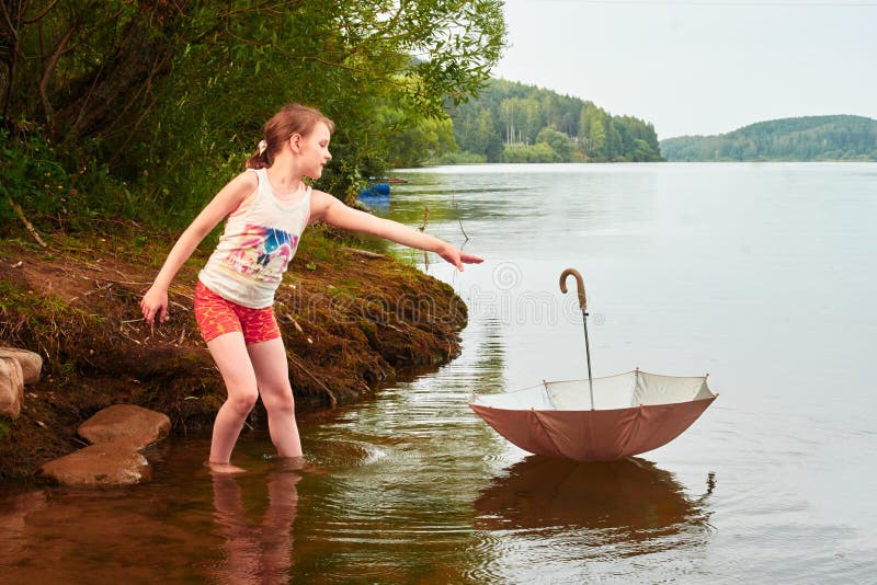La niña perdió su paraguas en día nublado en el lago imágenes de archivo libres de regalías La niña perdió su paraguas en día nublado en el lago imágenes de archivo libres de regalías