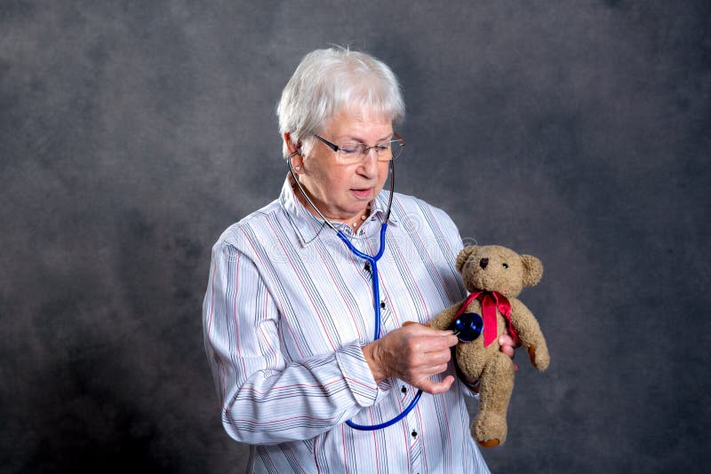 La nonna con lo stetoscopio ? medico del burattino per l'orsacchiotto fotografia stock