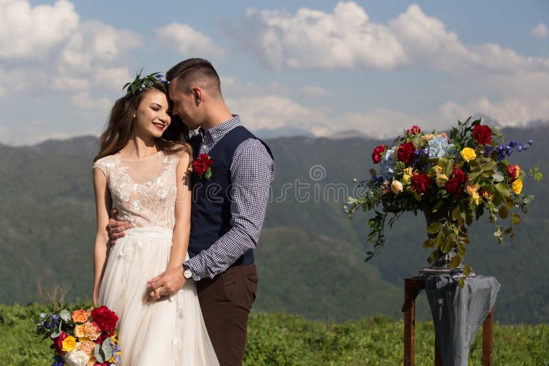 La novia y el novio en el fondo de una montaña fluyen fotos de archivo