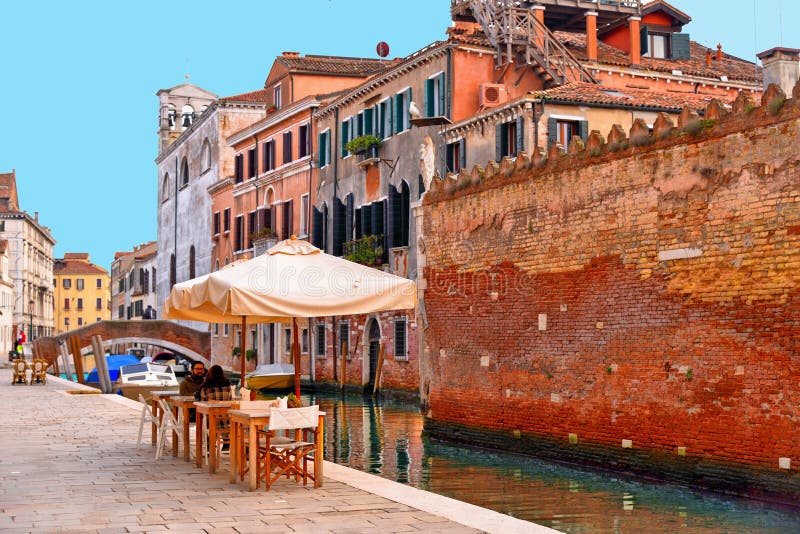 La ojeada de Venecia con uno de sus canales con los barcos, los edificios históricos y la gente beben y se relajan en tabla al ai