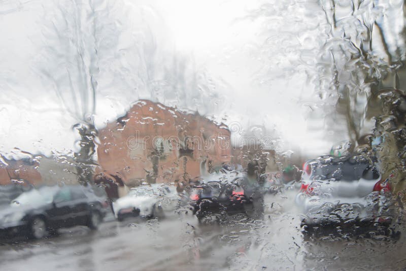 La opinión del camino a través del parabrisas del coche con lluvia cae, conduciendo en lluvia imagen de archivo La opinión del camino a través del parabrisas del coche con lluvia cae, conduciendo en lluvia imagen de archivo
