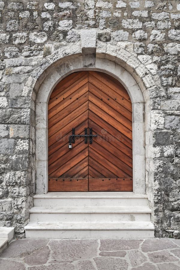 La pared de piedra de la fortaleza del castillo del castillo medieval, un a puerta cerrada de madera viejo con una cerradura imagenes de archivo La pared de piedra de la fortaleza del castillo del castillo medieval, un a puerta cerrada de madera viejo con una cerradura imagenes de archivo