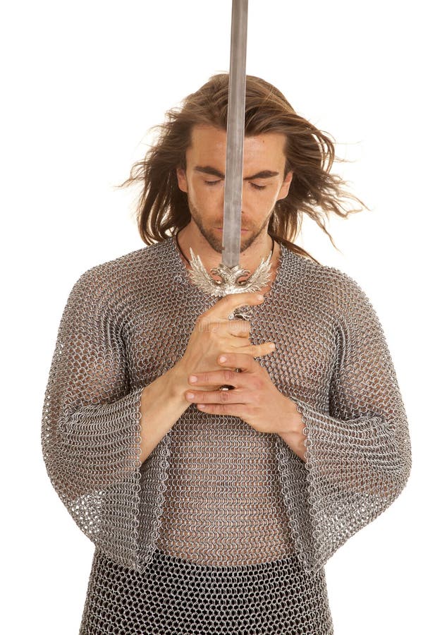 A man in his medieval chain mail leaning his head against his sword. A man in his medieval chain mail leaning his head against his sword.