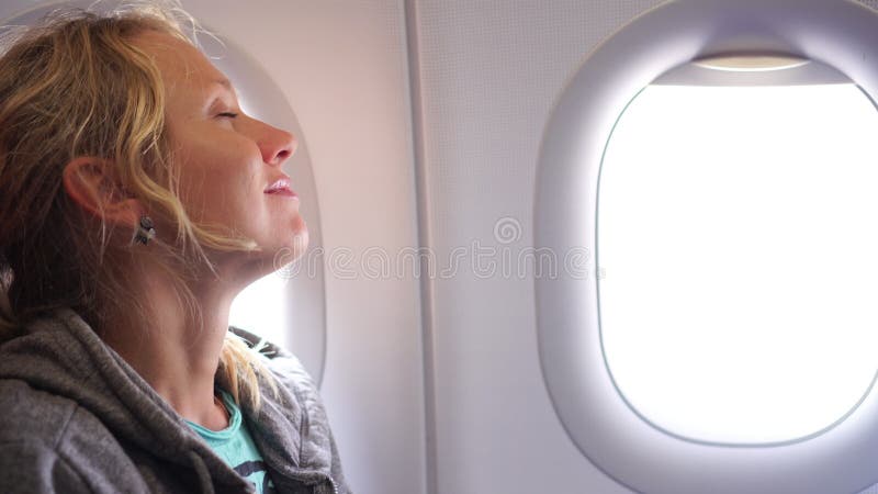 La passagère calme de femme vole dans un avion à côté de la fenêtre