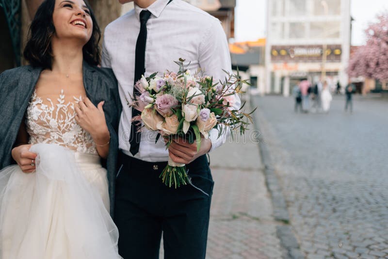 La passeggiata dello sposo e della sposa tramite le vie di una città europea Addolcisca gli abbracci fotografia stock La passeggiata dello sposo e della sposa tramite le vie di una città europea Addolcisca gli abbracci fotografia stock