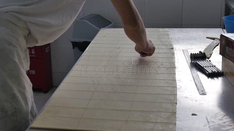 La pasta del corte del trabajador de la panadería cubre para los cruasanes en cocina industrial