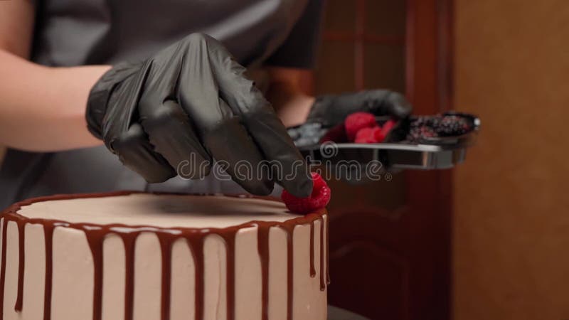 La pasticceria decora una torta utile con lamponi stock footage
