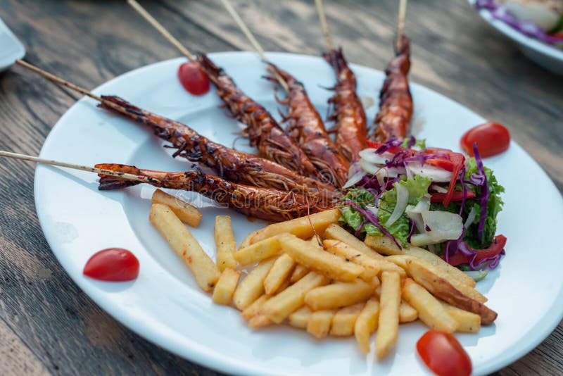 La patata fríe con las gambas de la fritada, ensalada de la lechuga Sobre fondo de madera imagenes de archivo La patata fríe con las gambas de la fritada, ensalada de la lechuga Sobre fondo de madera imagenes de archivo