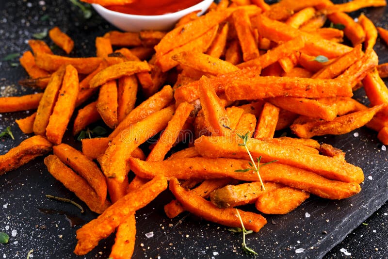 La patate douce orange cuite au four faite maison saine fait frire avec le ketchup, les herbes, le sel et le poivre photos stock La patate douce orange cuite au four faite maison saine fait frire avec le ketchup, les herbes, le sel et le poivre photos stock