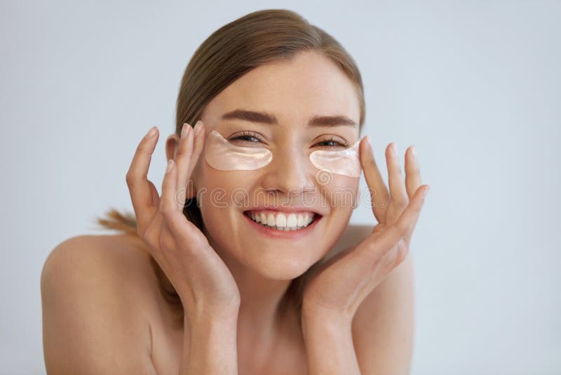 Eye skin beauty. Happy woman with transparent under eye patch, beauty mask on face portrait. Smiling girl using translucent collagen pad on white background. Eye skin beauty. Happy woman with transparent under eye patch, beauty mask on face portrait. Smiling girl using translucent collagen pad on white background