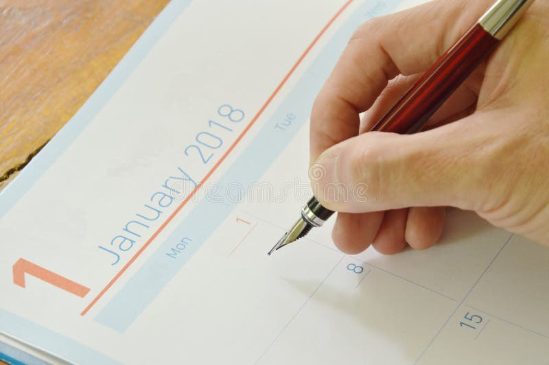 La penna stilografica della tenuta della mano scrive sul libro del giornale fotografia stock La penna stilografica della tenuta della mano scrive sul libro del giornale fotografia stock