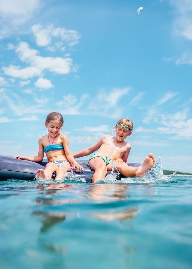 La pequeña hermana y el hermano se sientan en el colchón inflable en el mar Imagen feliz del concepto de las vacaciones de verano foto de archivo La pequeña hermana y el hermano se sientan en el colchón inflable en el mar Imagen feliz del concepto de las vacaciones de verano foto de archivo