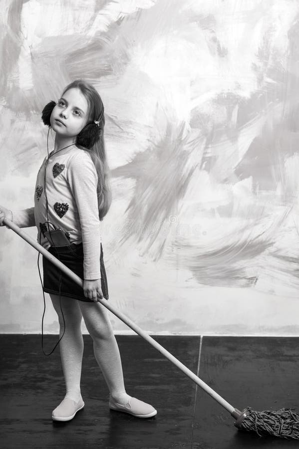 La pequeña muchacha escucha música con la fregona imagenes de archivo La pequeña muchacha escucha música con la fregona imagenes de archivo