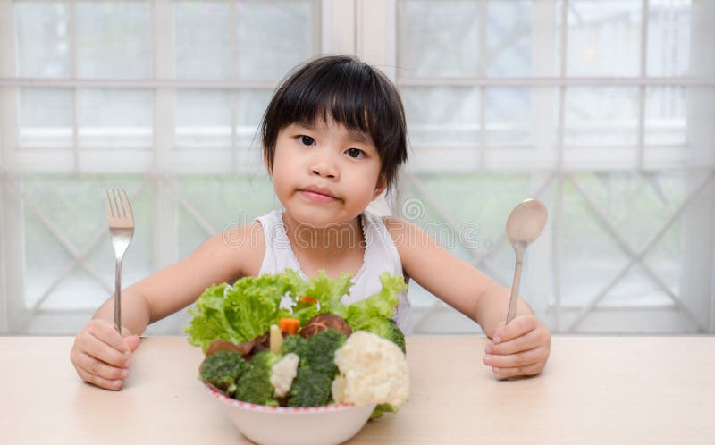 La pequeña muchacha sonriente dulce linda joven come la ensalada fresca/el concepto sano de la consumición imagen de archivo libre de regalías La pequeña muchacha sonriente dulce linda joven come la ensalada fresca/el concepto sano de la consumición imagen de archivo libre de regalías