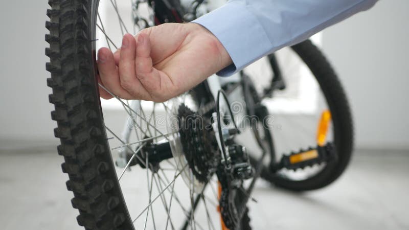 La persona di affari nel negozio della bicicletta controlla la pressione d'aria da una gomma