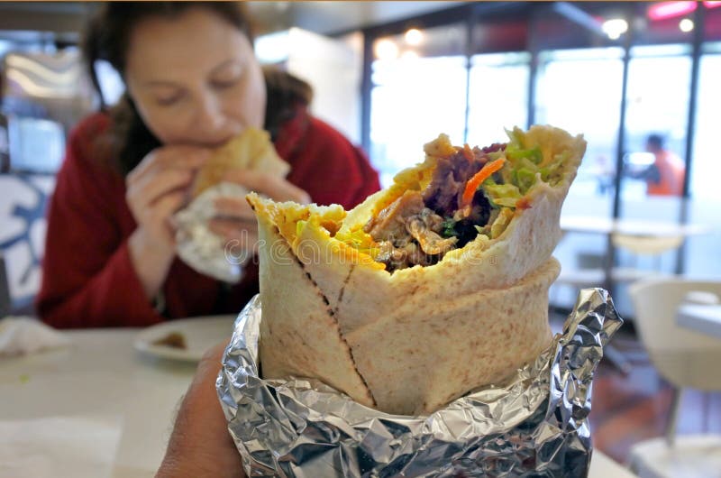 La personne mange l'enveloppe de chiche-kebab photo stock La personne mange l'enveloppe de chiche-kebab photo stock