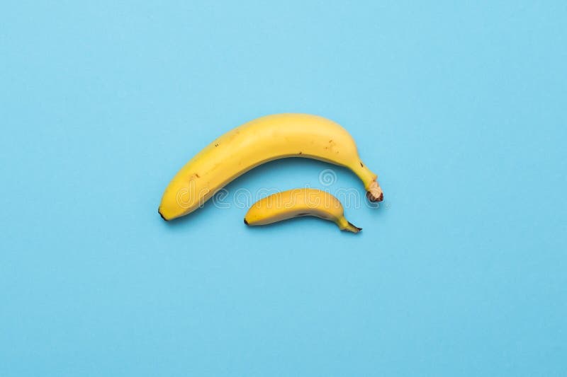 La petite banane comparent la taille à la banane sur le fond bleu concept de pénis de taille photo libre de droits La petite banane comparent la taille à la banane sur le fond bleu concept de pénis de taille photo libre de droits