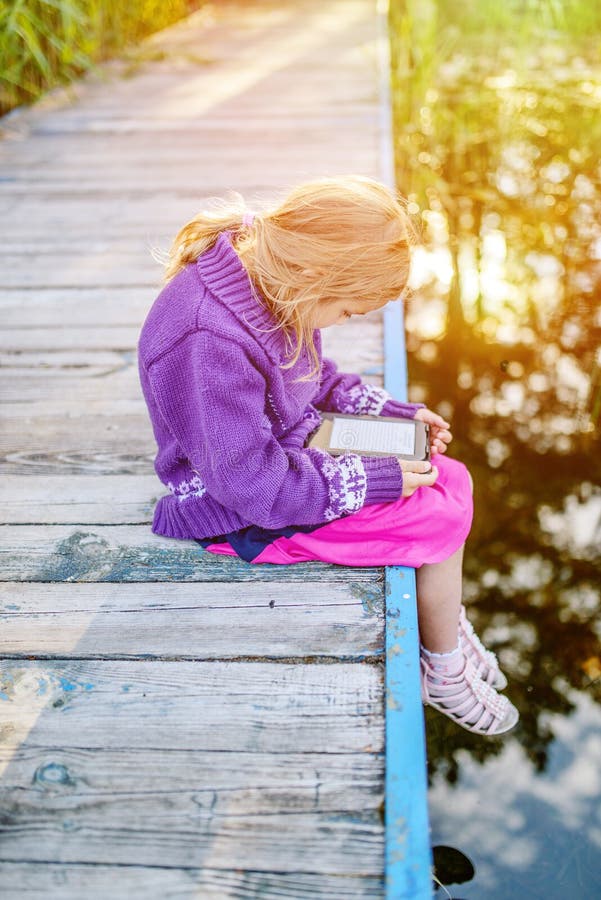 La petite belle fille a lu des e-livres photos stock La petite belle fille a lu des e-livres photos stock