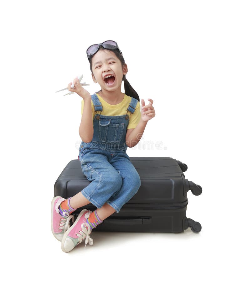 La petite fille asiatique tient un avion dans sa main et s'assied sur son lugg photos stock La petite fille asiatique tient un avion dans sa main et s'assied sur son lugg photos stock