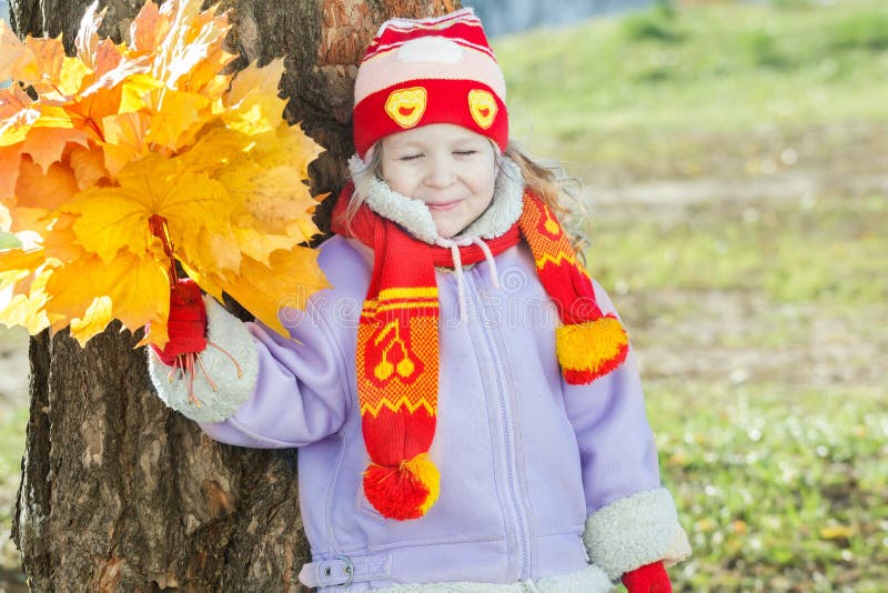 La petite fille de sourire jugeant jaune avec les feuilles d'automne oranges lient le portrait extérieur disponible images libres de droits