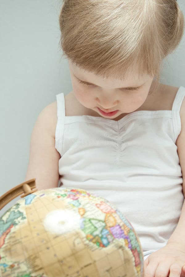 La petite fille examinant un globe photo libre de droits La petite fille examinant un globe photo libre de droits