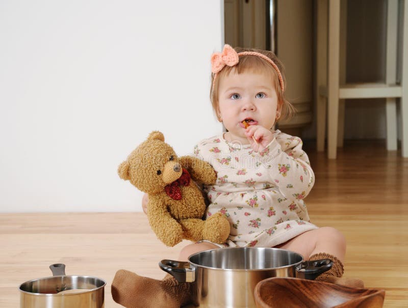 La petite fille faisant cuire avec le nounours concernent le plancher photo libre de droits La petite fille faisant cuire avec le nounours concernent le plancher photo libre de droits
