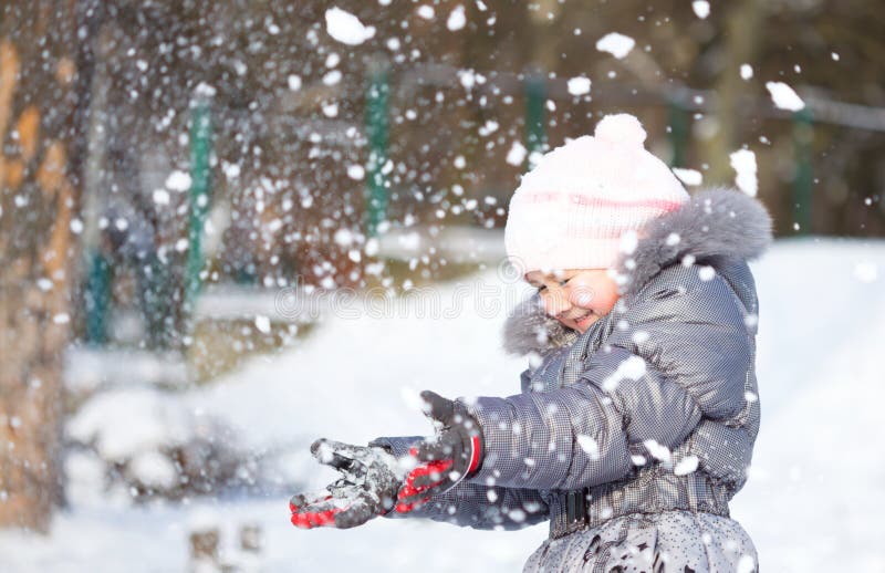 La petite fille jette la neige image stock La petite fille jette la neige image stock