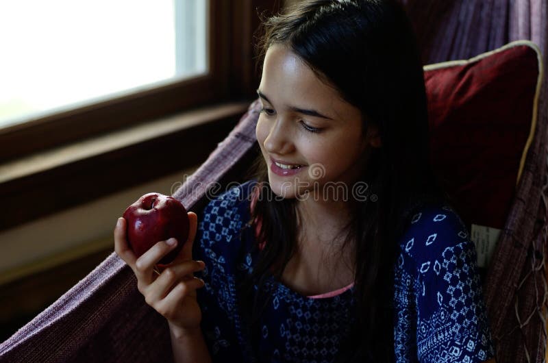 La petite fille mange une pomme dans un hamac photos libres de droits La petite fille mange une pomme dans un hamac photos libres de droits
