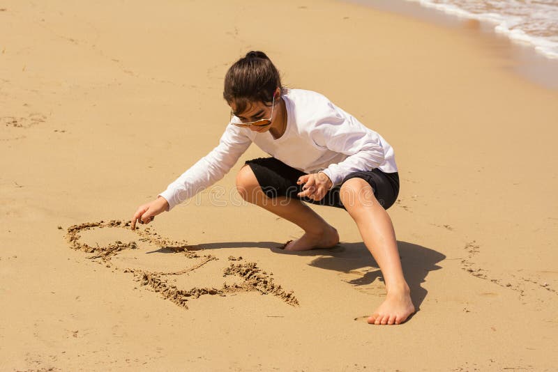 La petite fille me dessine aiment sur le sable images libres de droits La petite fille me dessine aiment sur le sable images libres de droits