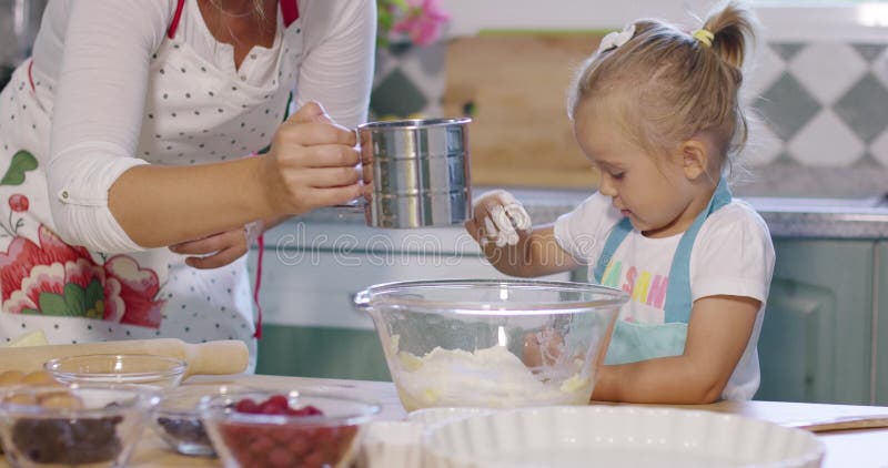 La petite fille mignonne aidant sa mère font une tarte cuire au four