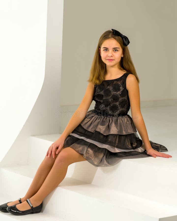 La petite fille mignonne est assis dans le studio dans l'escalier blanc. Enfance heureuse du concept de style et de mode.
