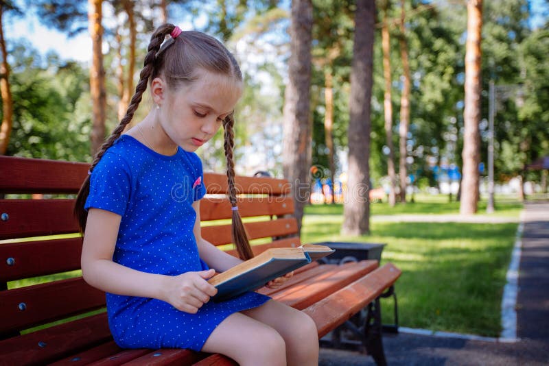 La petite fille mignonne lit un livre dehors photo libre de droits La petite fille mignonne lit un livre dehors photo libre de droits