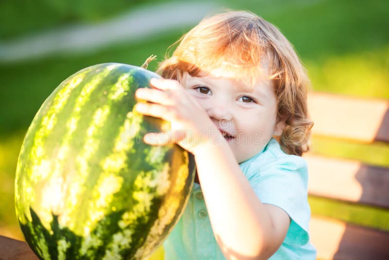 La petite fille mignonne mange une tranche de pastèque dehors photos libres de droits La petite fille mignonne mange une tranche de pastèque dehors photos libres de droits