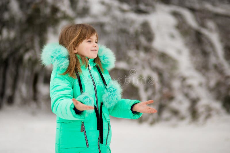 La petite fille mignonne étire sa main pour attraper les flocons de neige en baisse photos libres de droits La petite fille mignonne étire sa main pour attraper les flocons de neige en baisse photos libres de droits