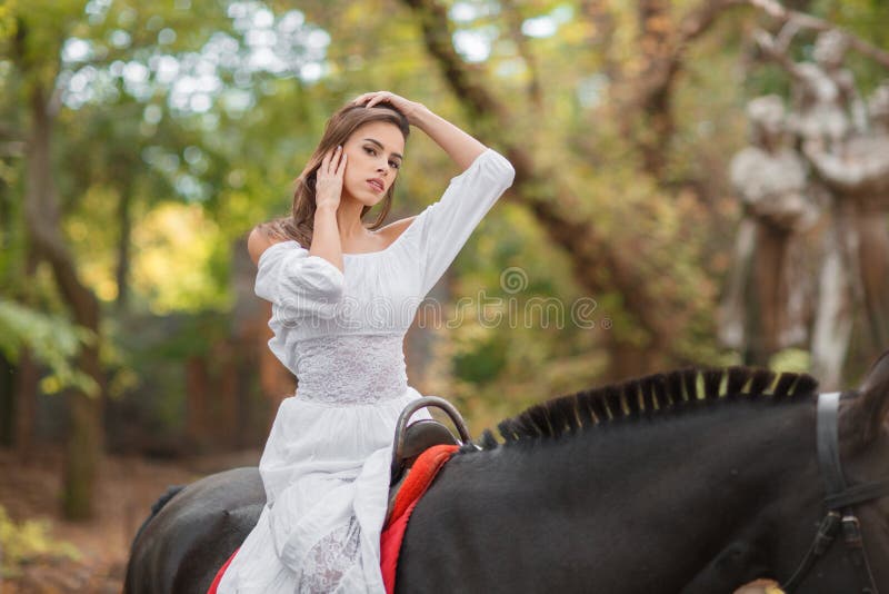 Bonne Petite Fille Avec Une Longue Queue De Cheval Jusqu'à Ses Épaules, Et  Un Arc Rouge Sur La Tête, Dans Une Belle Robe D'été. Fille Étreignant Un  Gros Ours En Peluche. Fermer