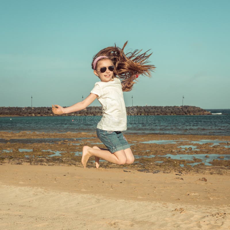 La petite fille sautent sur une plage photographie stock La petite fille sautent sur une plage photographie stock