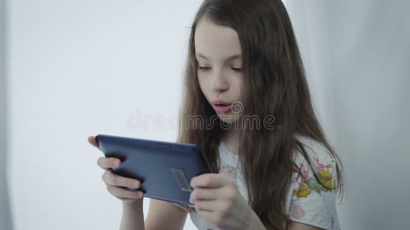 La petite fille émotive joue un jeu sur le comprimé