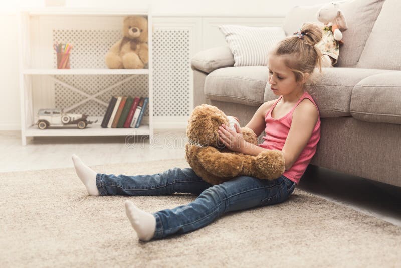 La petite fille étreignant son nounours concernent le plancher photos stock La petite fille étreignant son nounours concernent le plancher photos stock