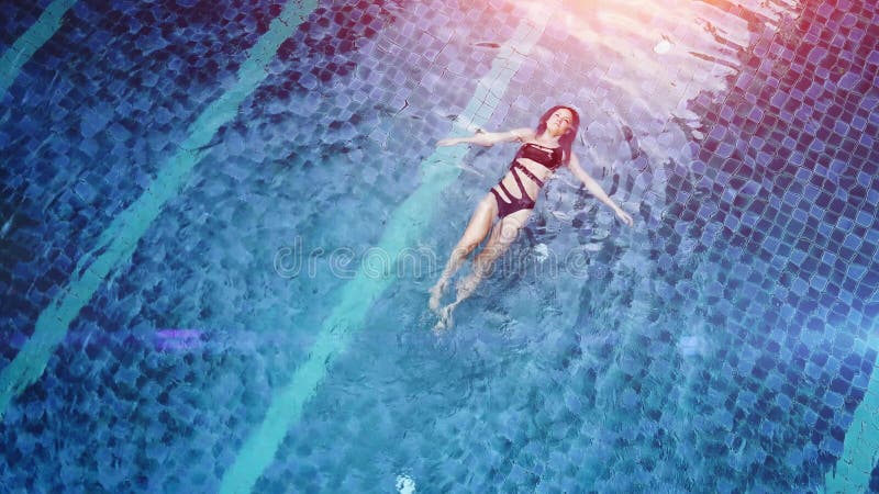 La photo aérienne de vue de dessus d'un modèle sexy séduisant dans des maillots de bain noirs apprécie vous détendre dans la pisci banque de vidéos